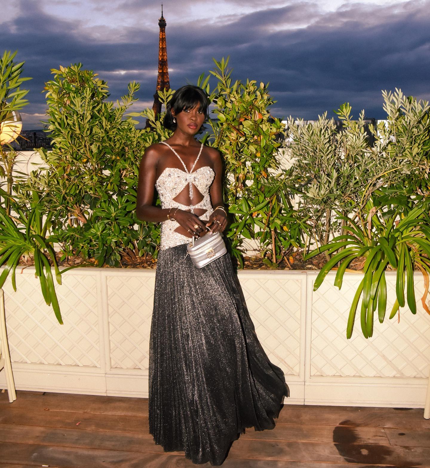 A guest in an embellished bow bodice and metallic pleated skirt on the rooftop