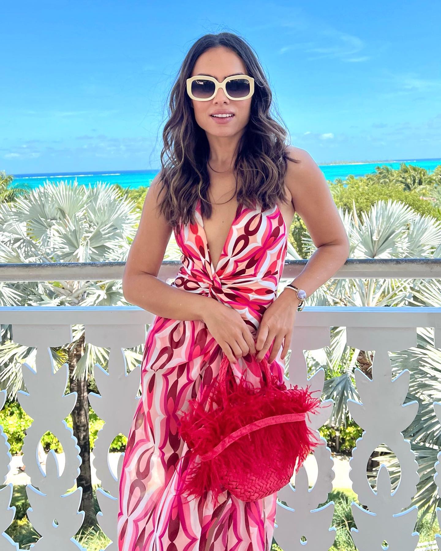 Influencer in a printed PatBO halter dress on a balcony over the palms